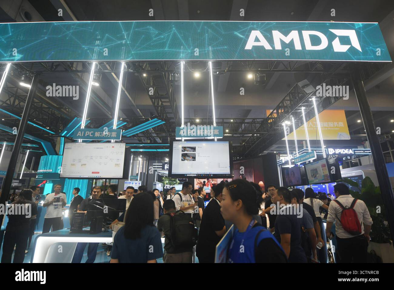 Visitors pass by the booth of AMD during a tech fair in Hangzhou in ...
