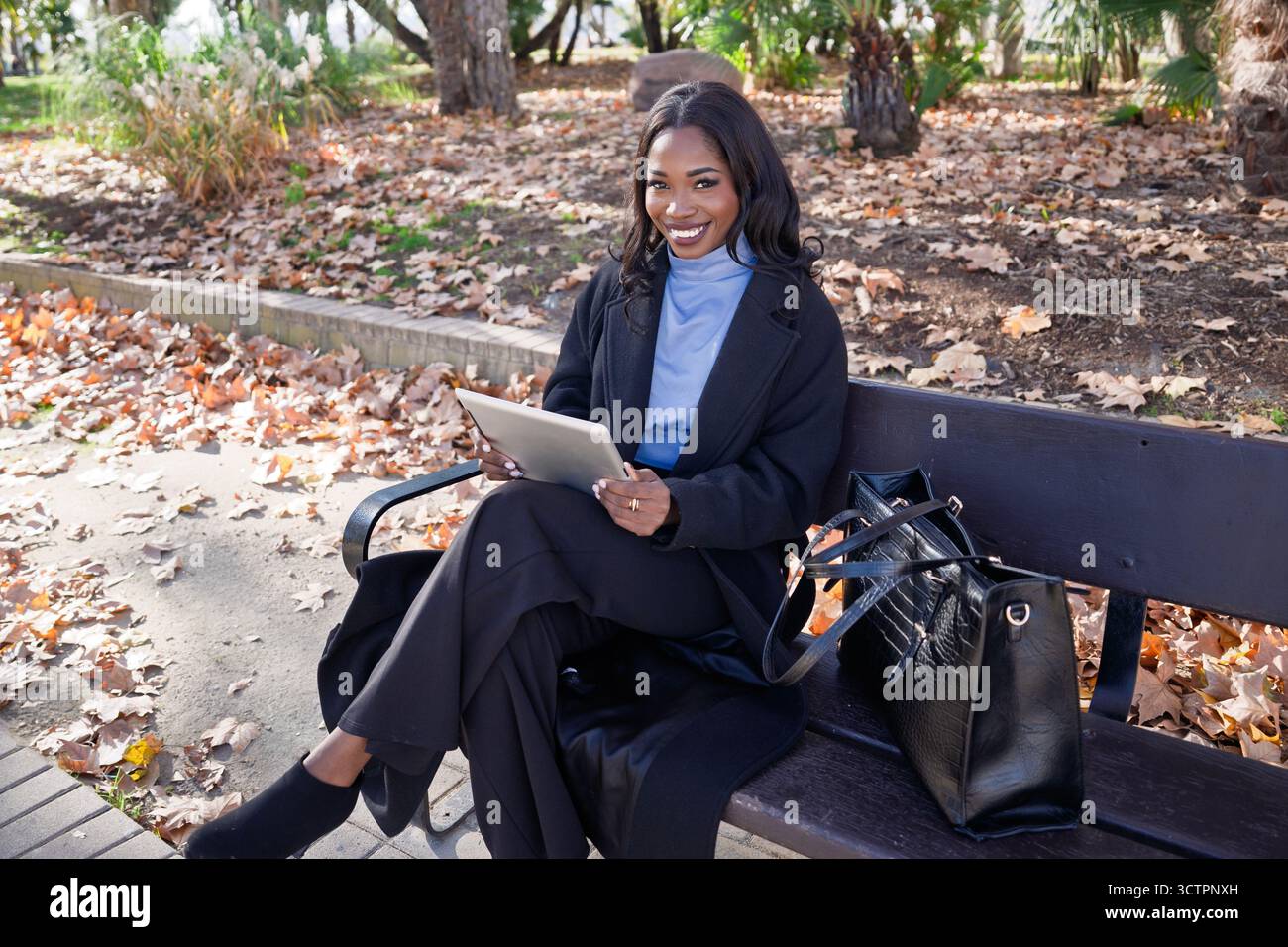 African american executive working outdoors, enjoying technology during autumn Stock Photo