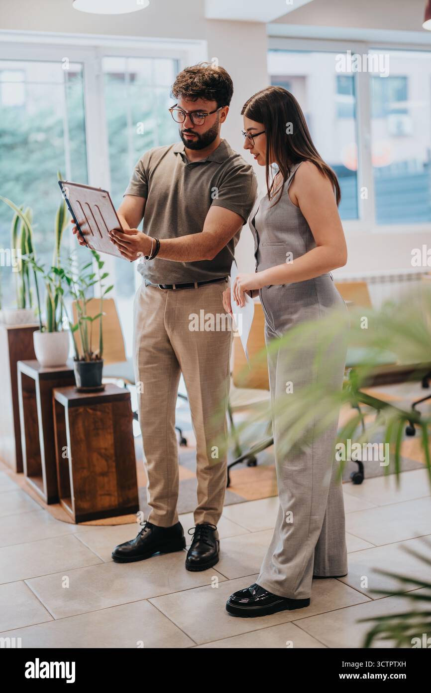 Colleagues Discussing Data on a Tablet in a Bright Office Space Stock Photo
