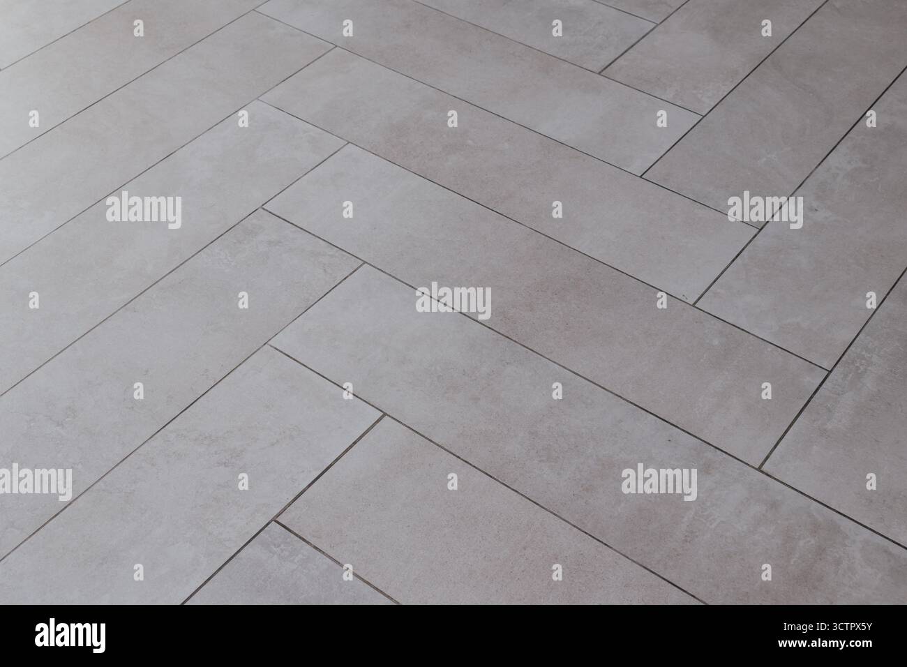 Grey rectangular tile texture in herringbone pattern imitating natural stone. Stock Photo