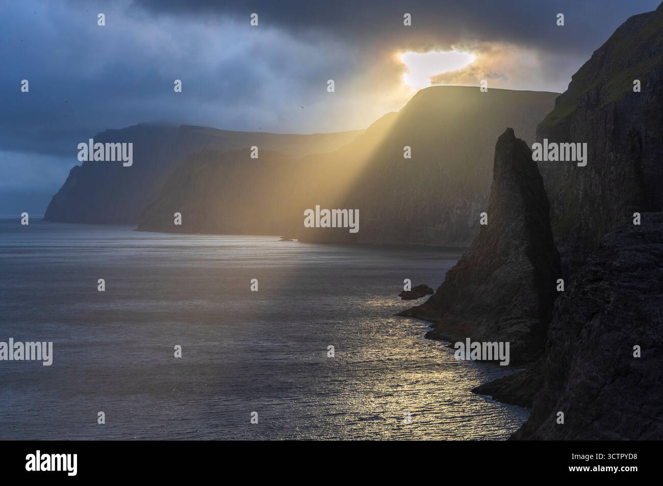 View of a sea stack near Bøsdalafossur waterfall and Sørvagsvatn at sunset in spring. Vagar, Faroe Islands, Denmark, Scandinavia. Stock Photo