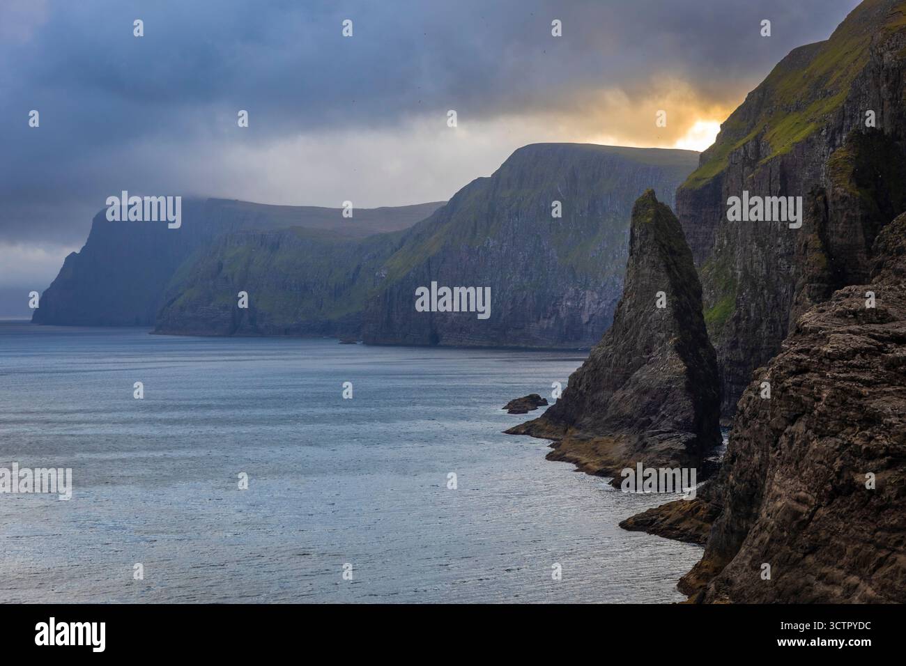 View of a sea stack near Bøsdalafossur waterfall and Sørvagsvatn at sunset in spring. Vagar, Faroe Islands, Denmark, Scandinavia. Stock Photo