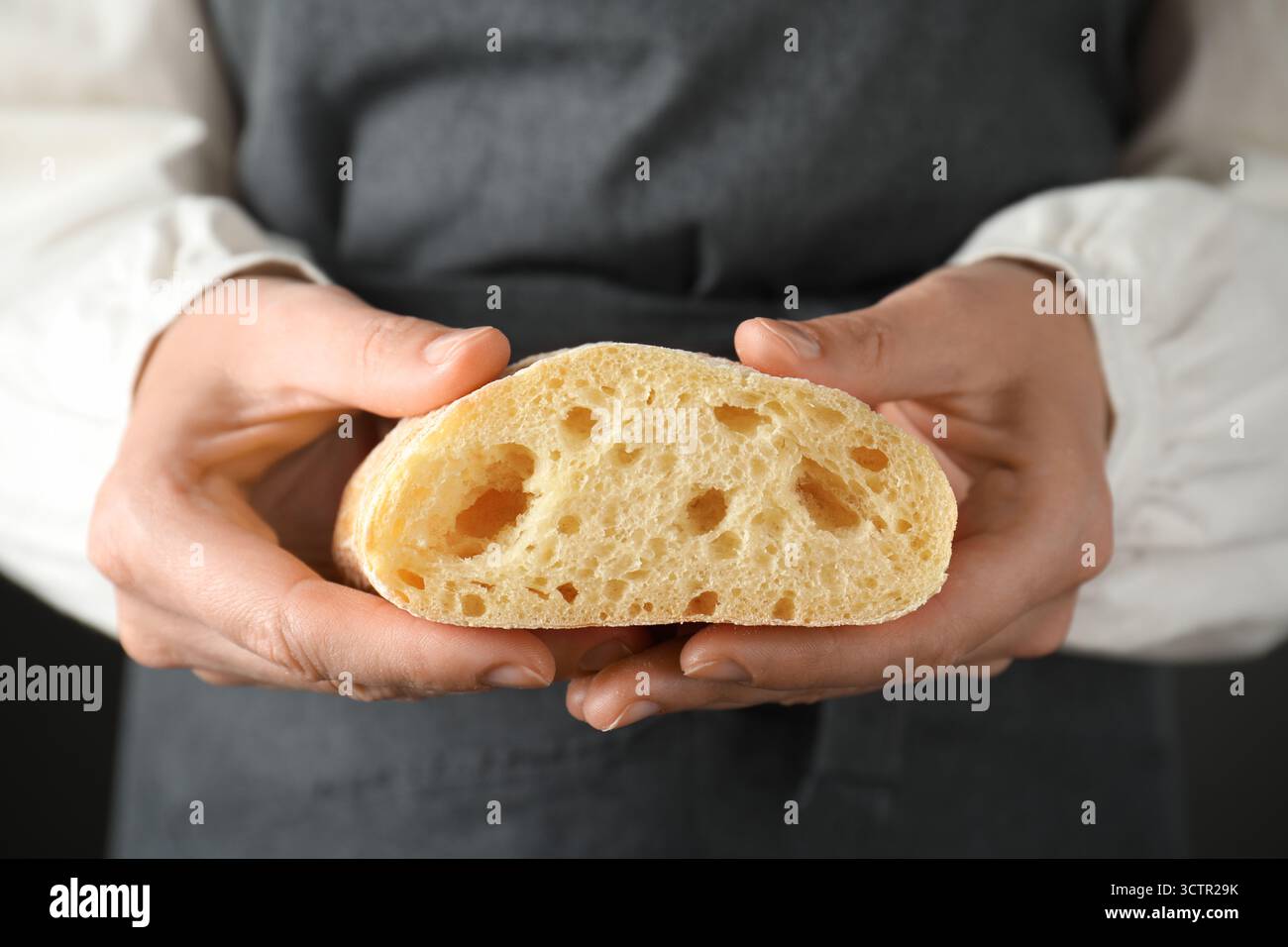Woman holding half of fresh crispy ciabatta, closeup Stock Photo