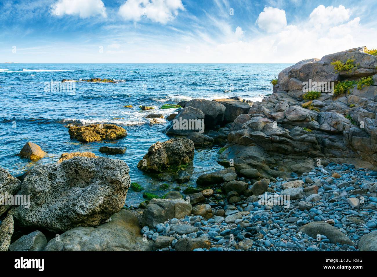 weekend on a rocky beach at the black sea under open blue sky. beautiful coastline of bulgaria in summer. seascape scenery on a bright morning with cl Stock Photo