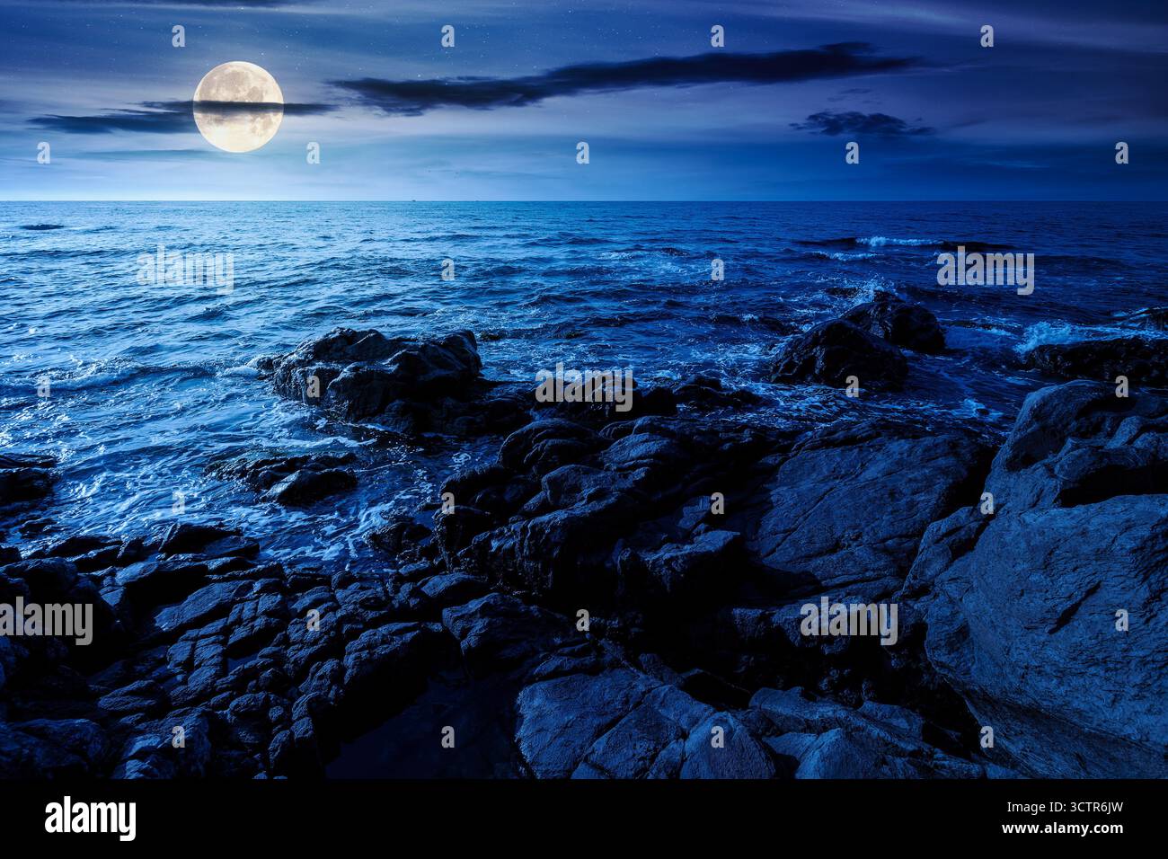 weekend on a rocky beach at the black sea under open dark sky at night. beautiful coastline in summer. seascape scenery with clouds above horizon in f Stock Photo