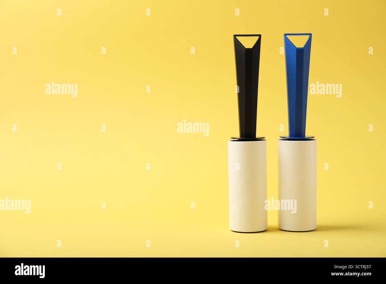 Two lint rollers on yellow background, space for text Stock Photo