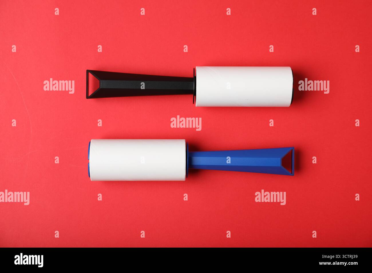 Two lint rollers on red background, flat lay Stock Photo