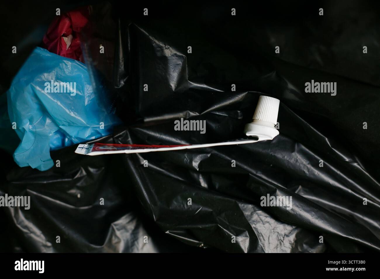Empty toothpaste tube on plastic trash bag Stock Photo