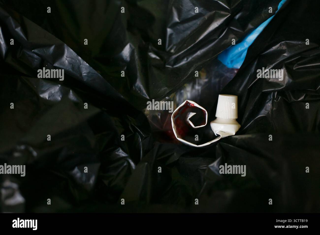 Empty toothpaste tube on plastic trash bag Stock Photo