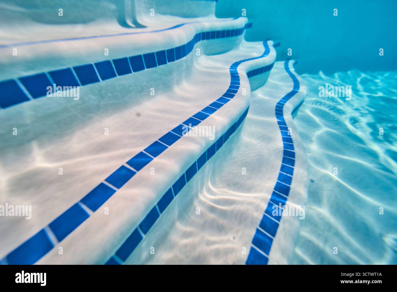 Underwater Pool Steps with Blue Tile and Sunlight Patterns in Neighborhood Setting Stock Photo