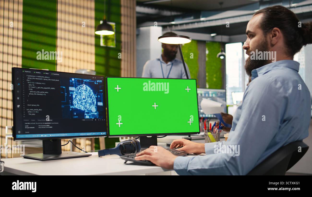 Technician in office using green screen PC, automating repetitive tasks with AI scripts. IT expert using artificial intelligence tech on mockup computer to speed up feature implementation, camera A Stock Photo