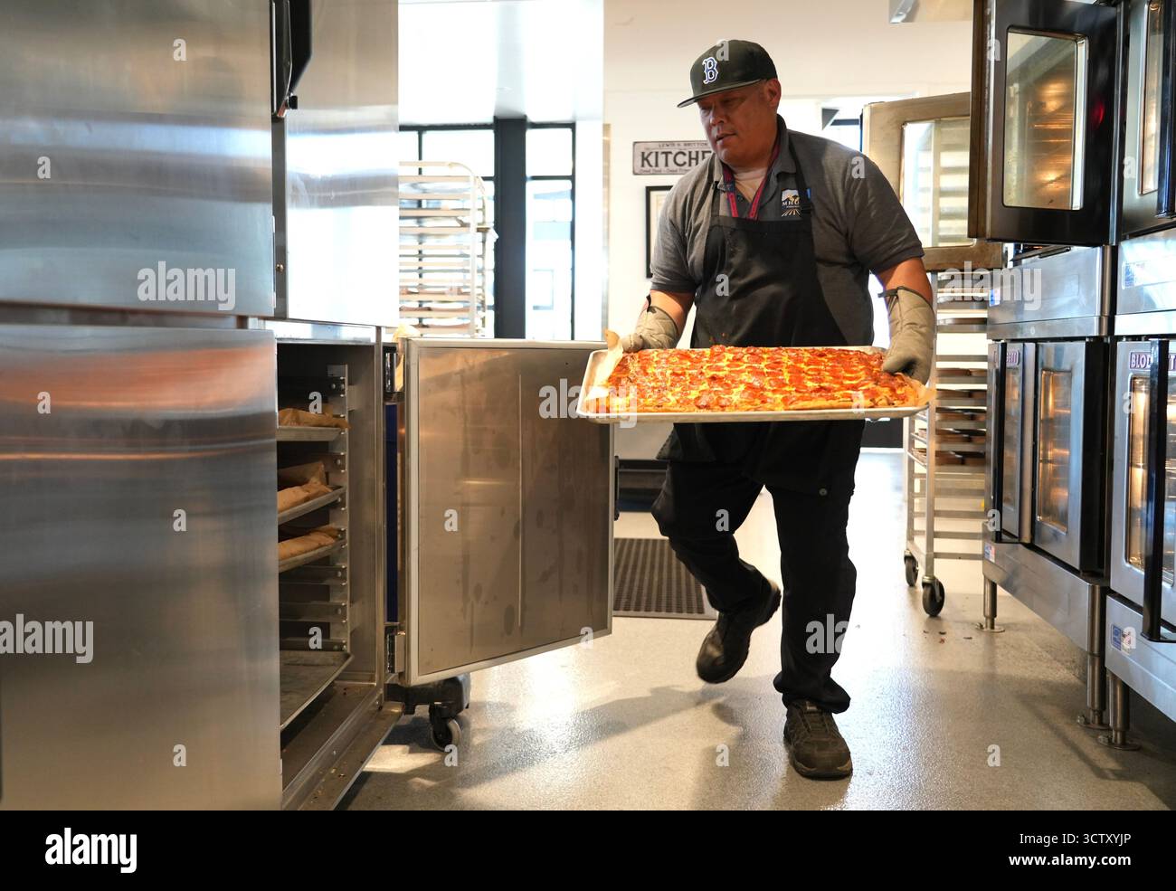 School cook Mark Pagaran carries a tray of freshly-made pizza at ...