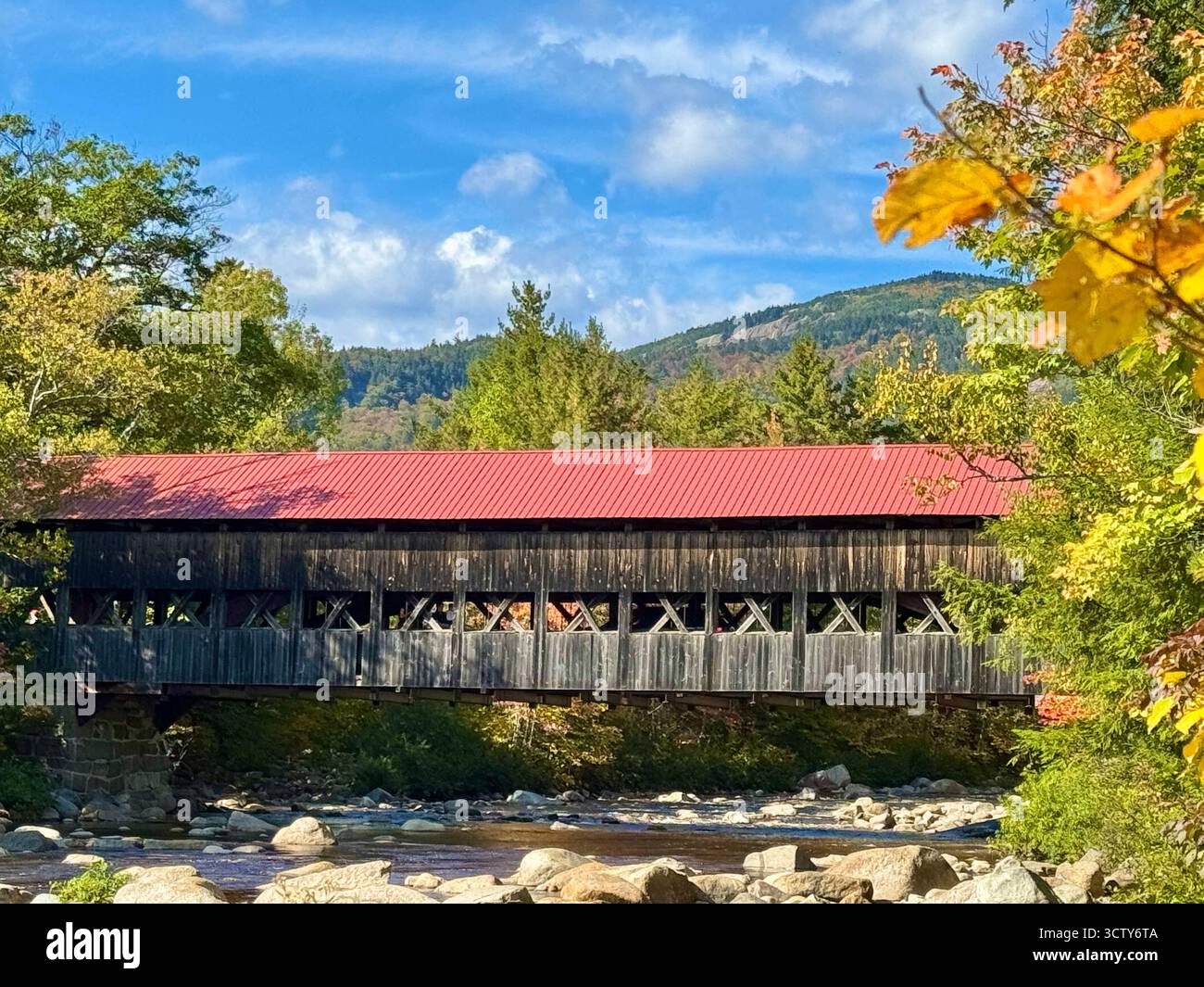 Albany Covered Bridge, spanning the Swift River in New Hampshire White Mountain National Park, surround by mountains and trees as autumn begins. - Smartphone Captured Stock Image