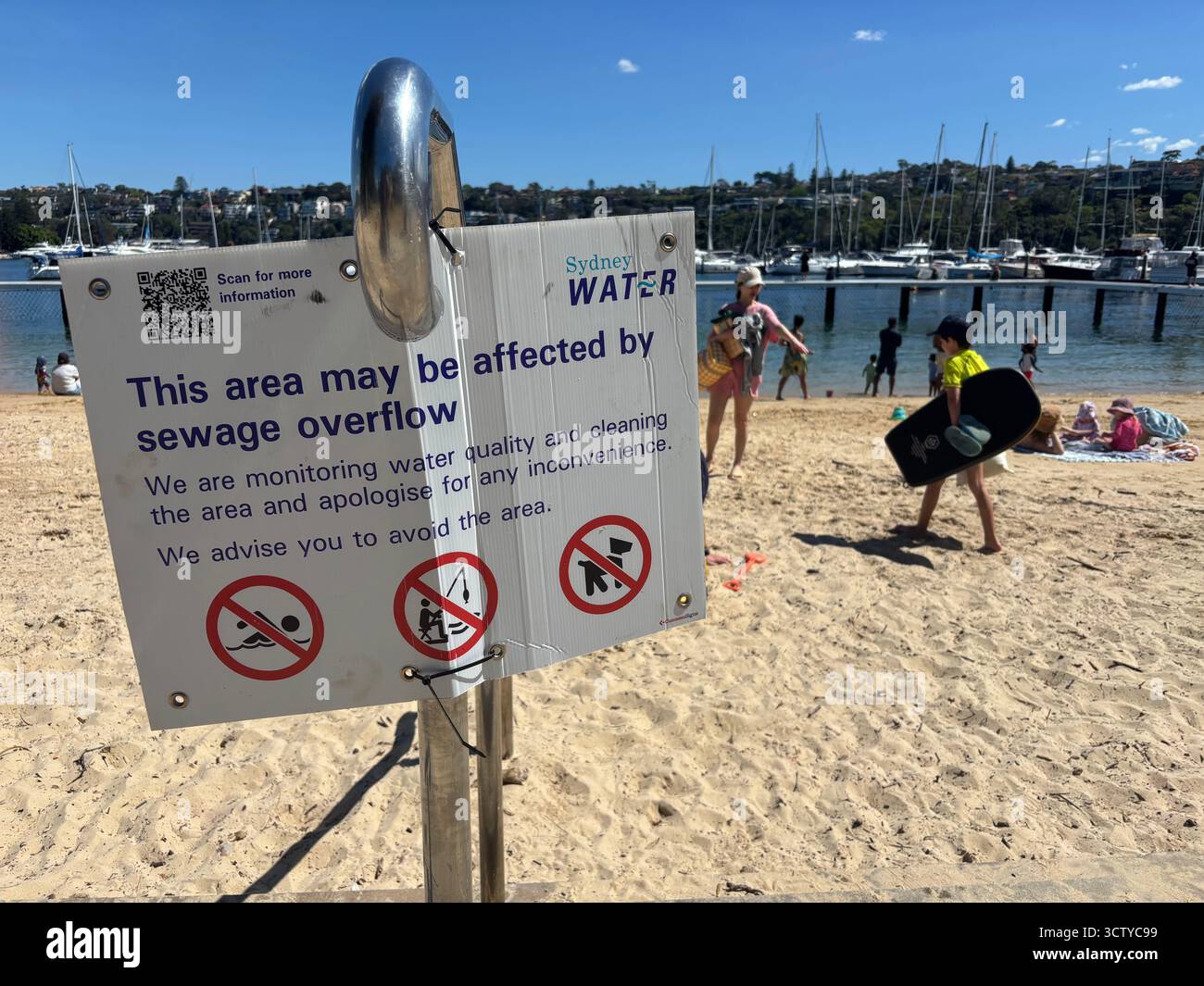 People on beach ignoring water quality warning sign, XXX beach, Sydney, NSW, Australia. No MR or PR Stock Photo