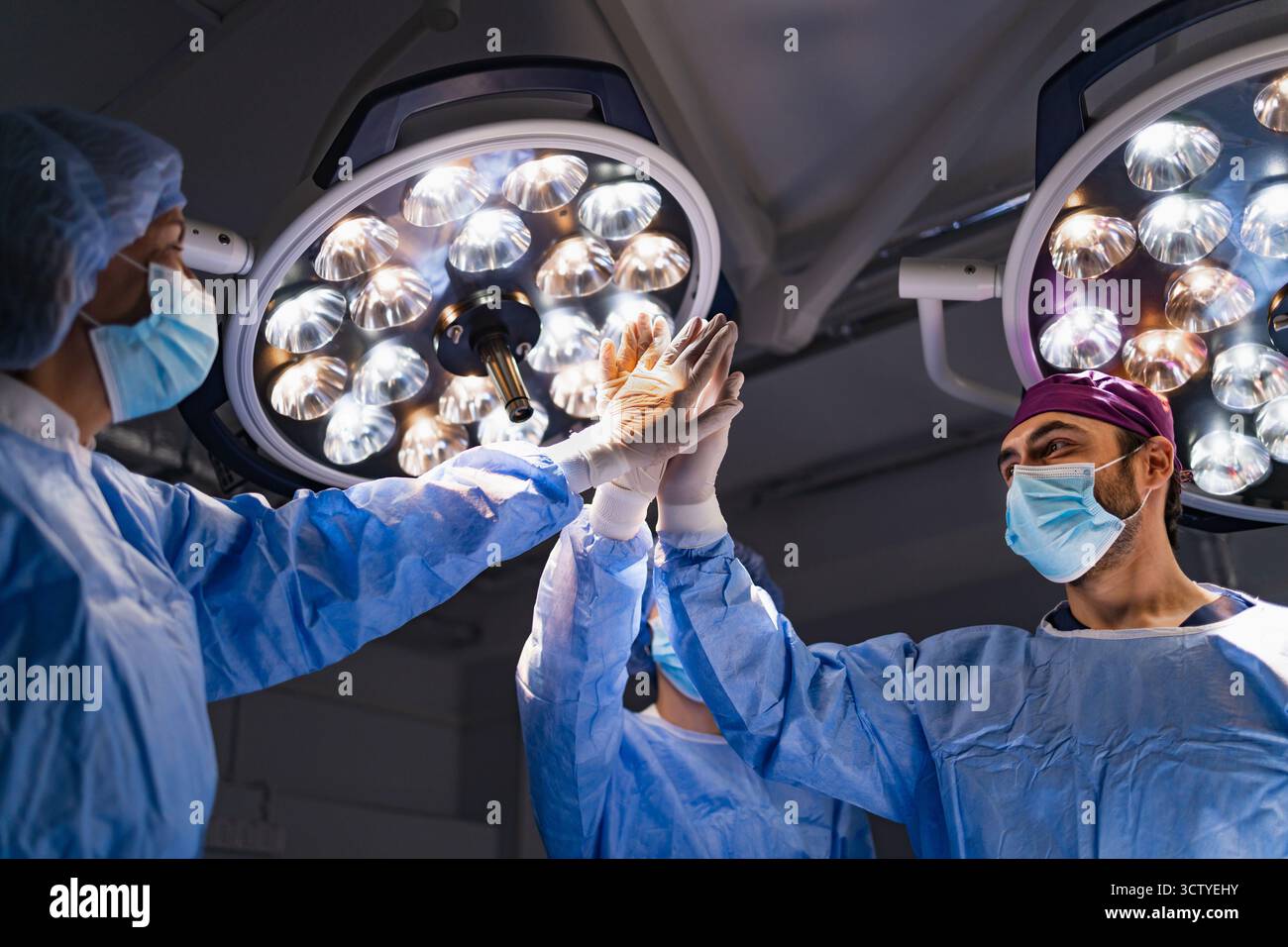 Surgeons Celebrate in Operating Room Stock Photo - Alamy