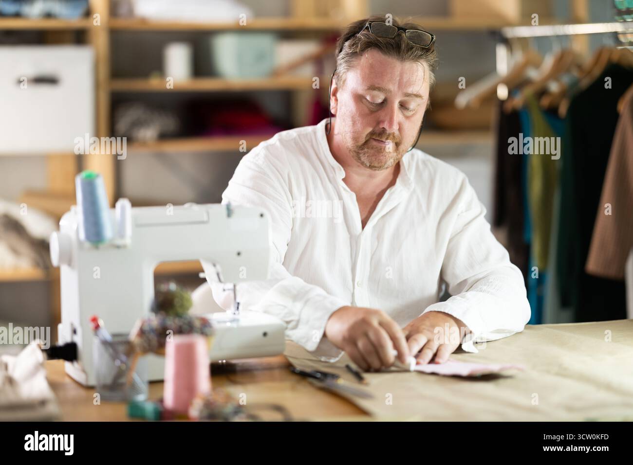 Middle-aged male dressmaker drawing detail on paper with chalk Stock Photo