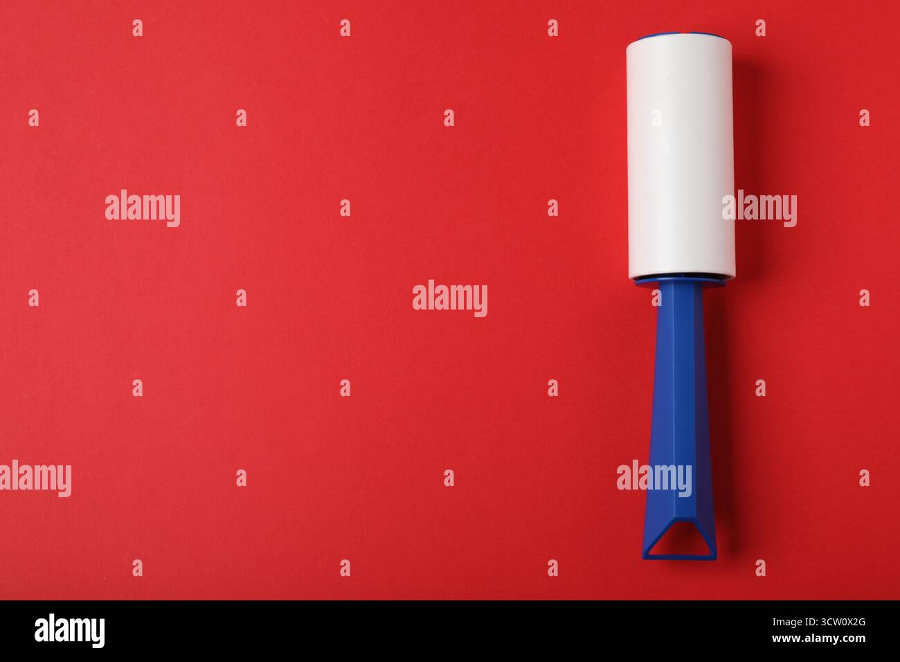 One lint roller on red background, top view. Space for text Stock Photo