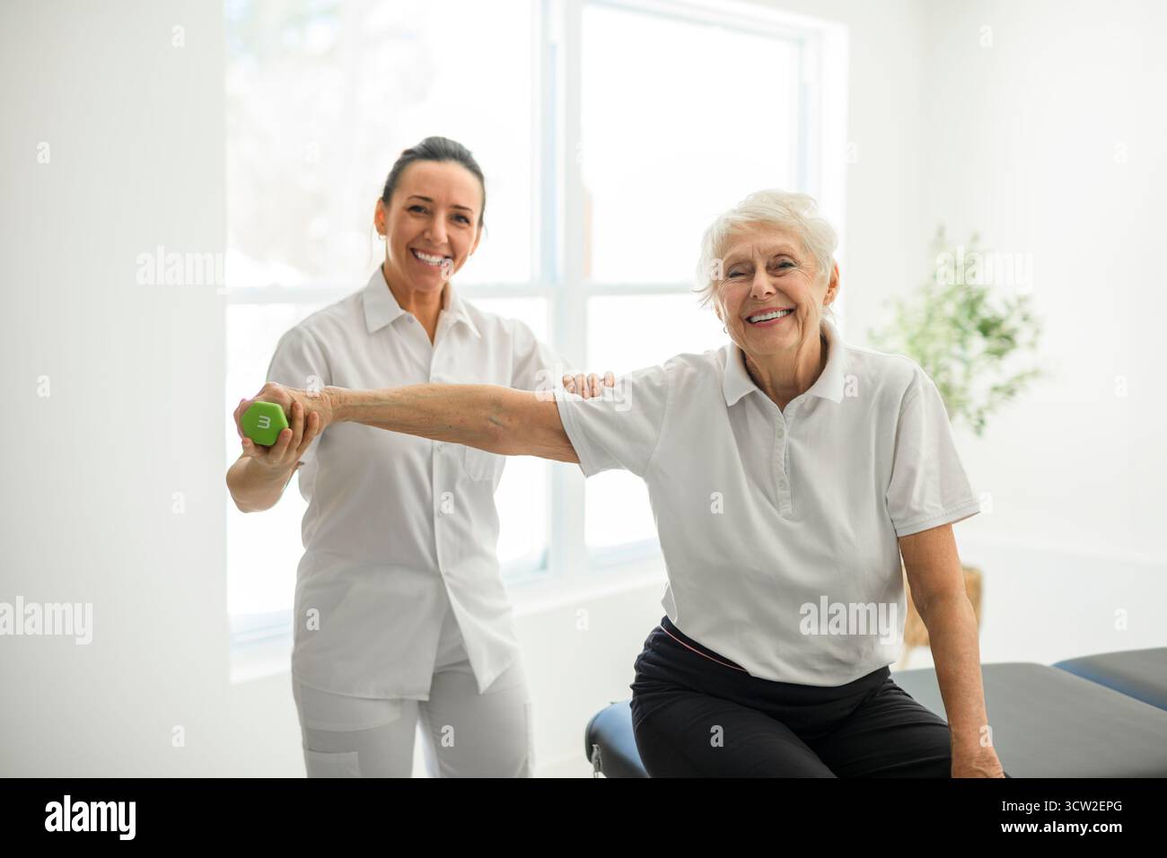 A physiotherapist helping senior woman in clinic. Elderly woman undergoing physiotherapy treatment for injury Stock Photo