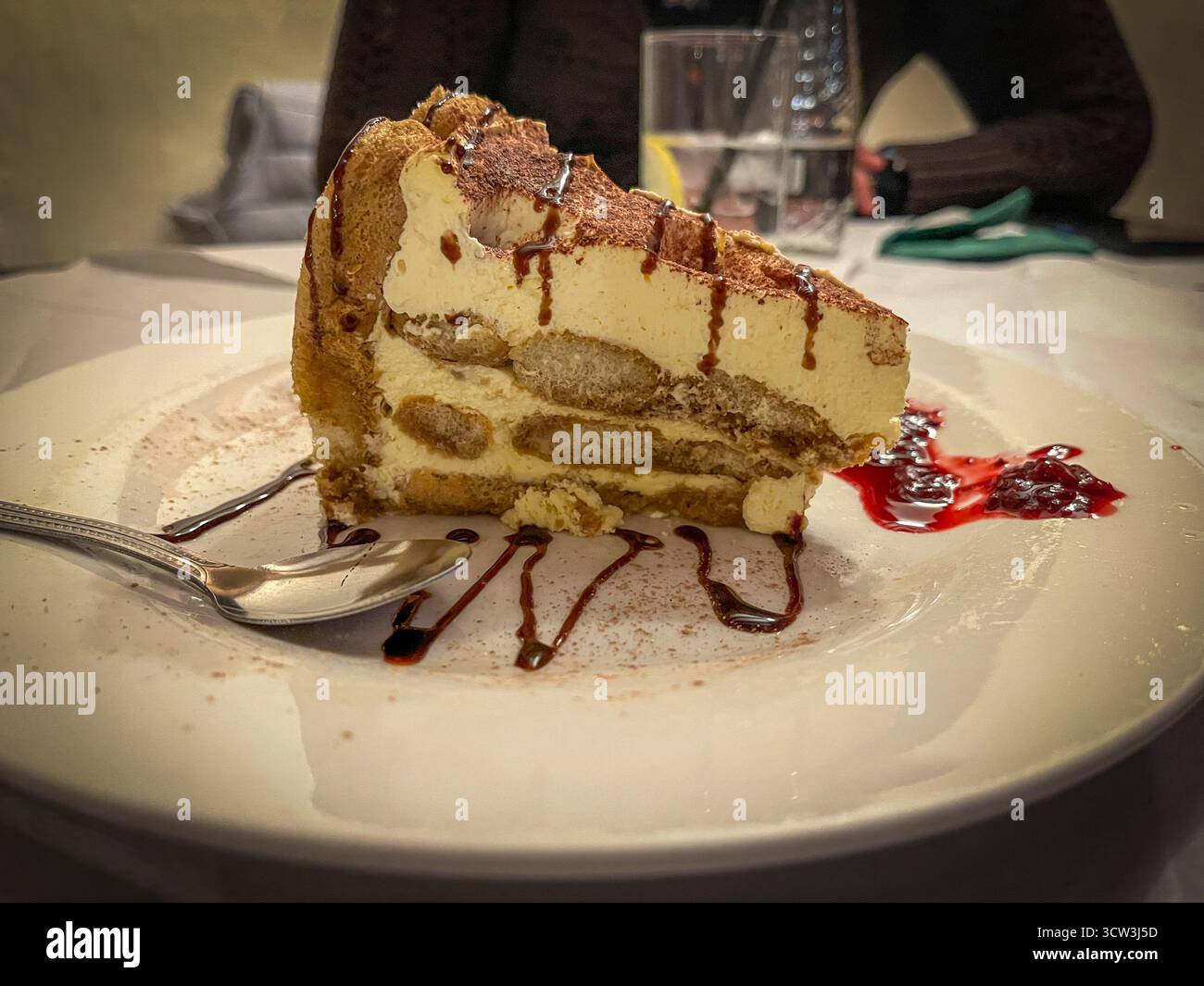 Elegant Tiramisu Dessert with Chocolate Drizzle and Fresh Strawberries in a Restaurant Setting - Smartphone Captured Stock Image