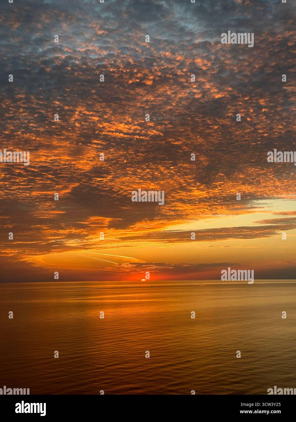 Sunset over the calm Black Sea near Poti, Georgia, with orange and purple clouds reflecting on the tranquil water at golden hour - Smartphone Captured Stock Image
