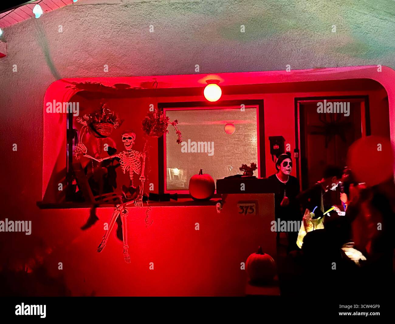 Halloween Porch with Skeletons, Pumpkins, and Trick-or-Treaters - Smartphone Captured Stock Image