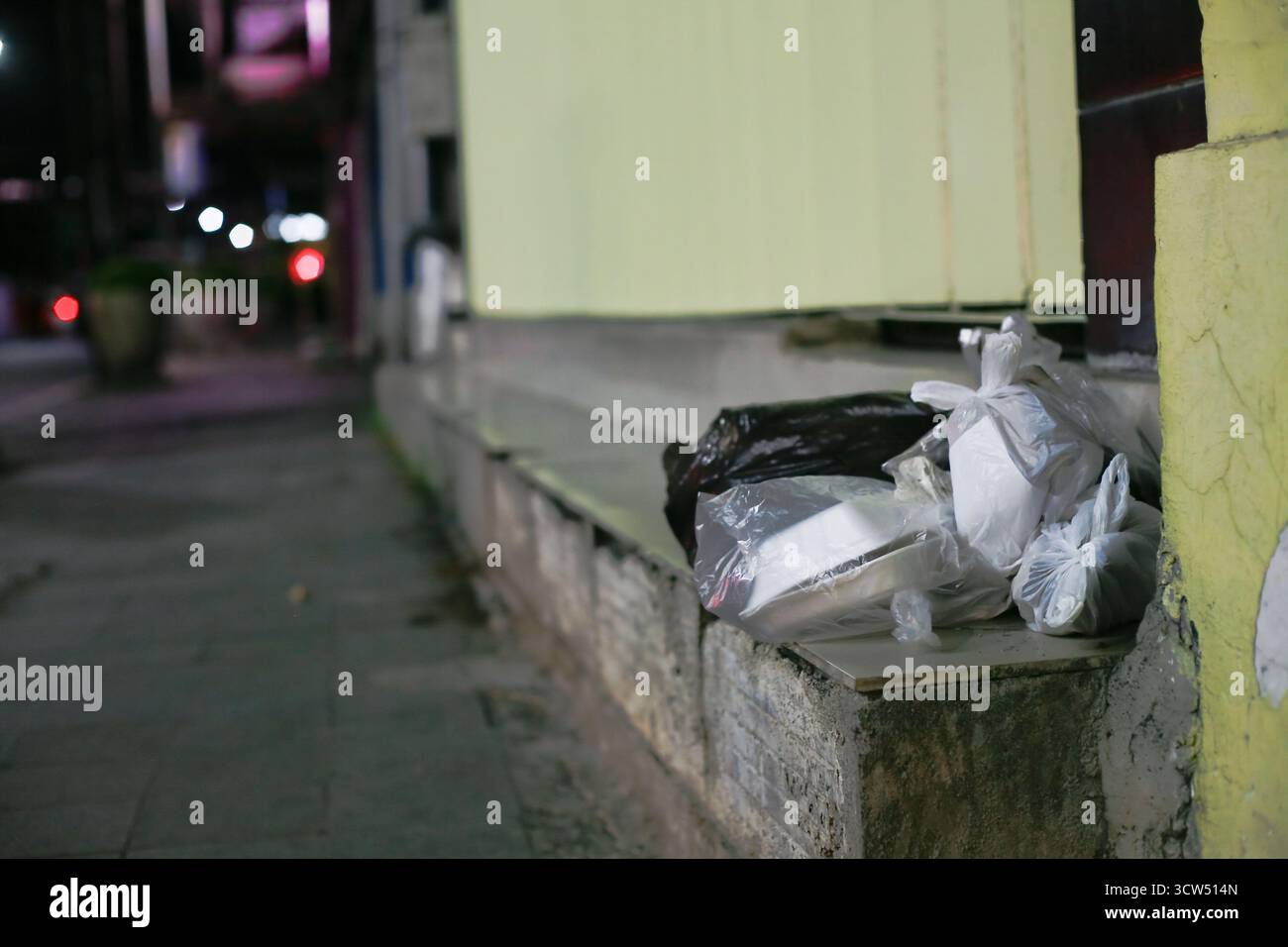 plastic takeaway packaging and foam boxes left on the side of the road at night Stock Photo