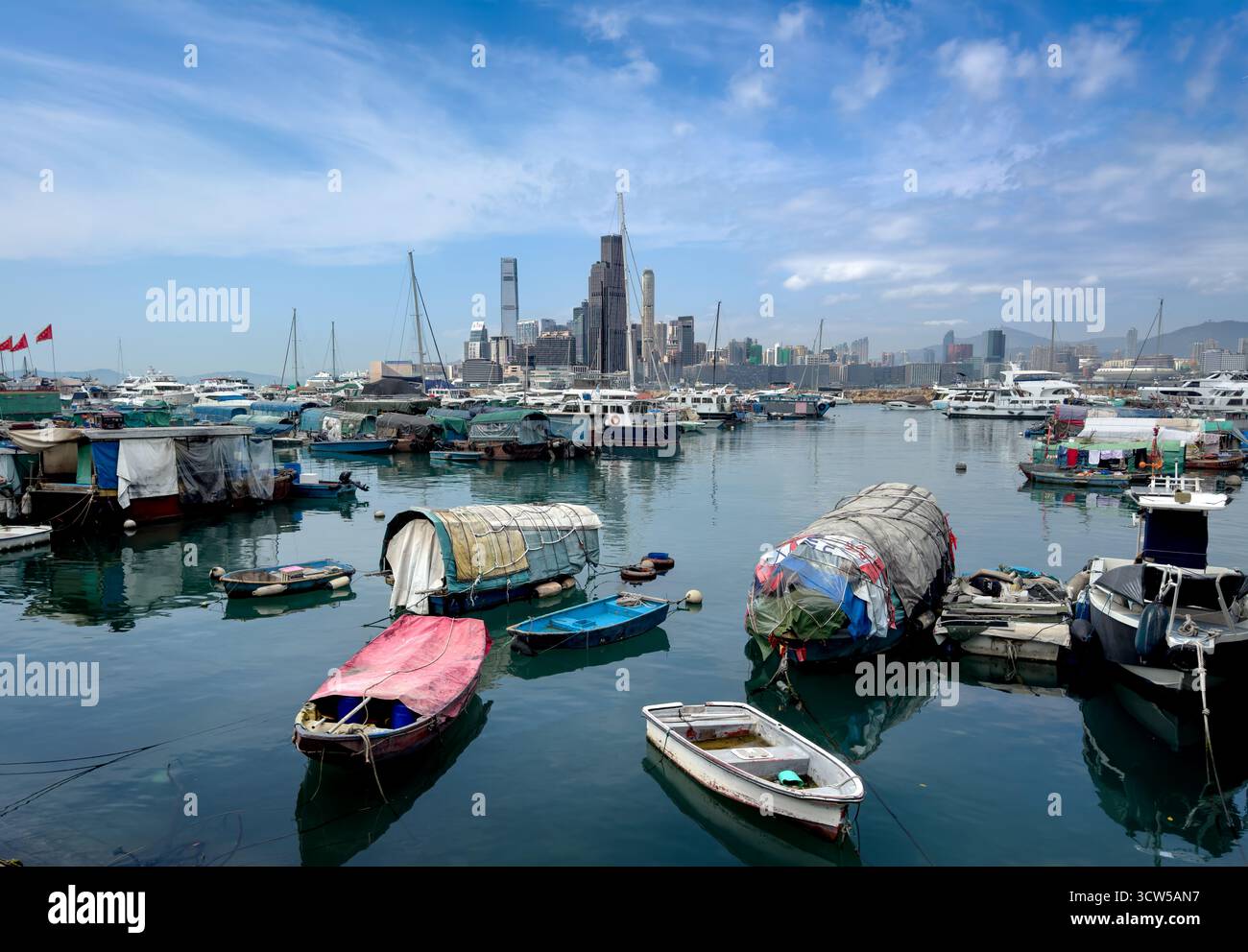 Kowloon and Victoria Harbor from Hong Kong Island with traditional fishing vessels, junks moored at the sea wall. Stock Photo