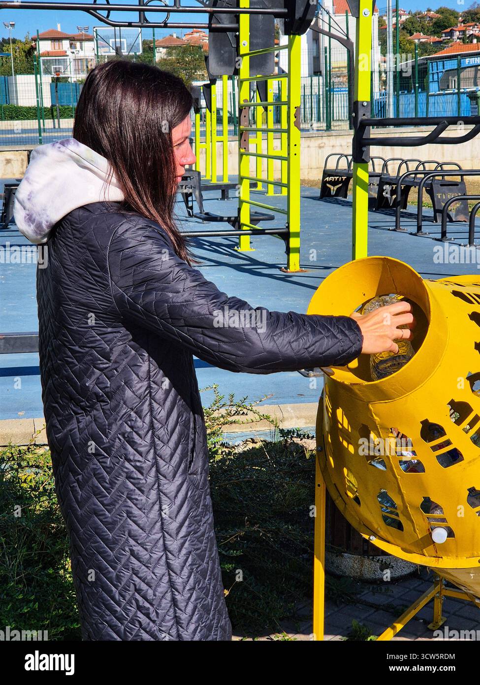 Disposal of garbage in a public park. woman recycling plastic bottle. - Smartphone Captured Stock Image