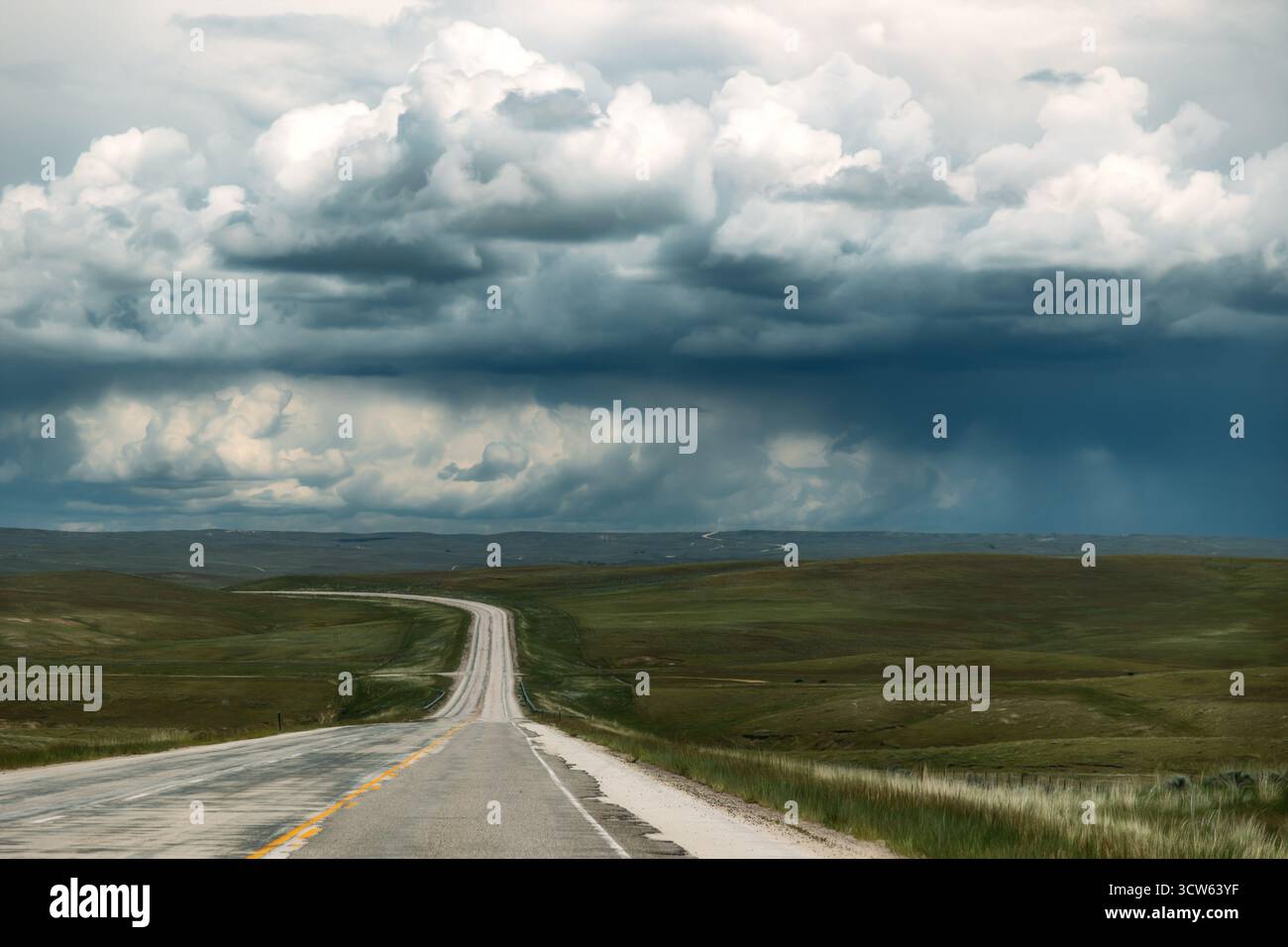 Long Empty Highway leading to Rainclouds in Distance Stock Photo