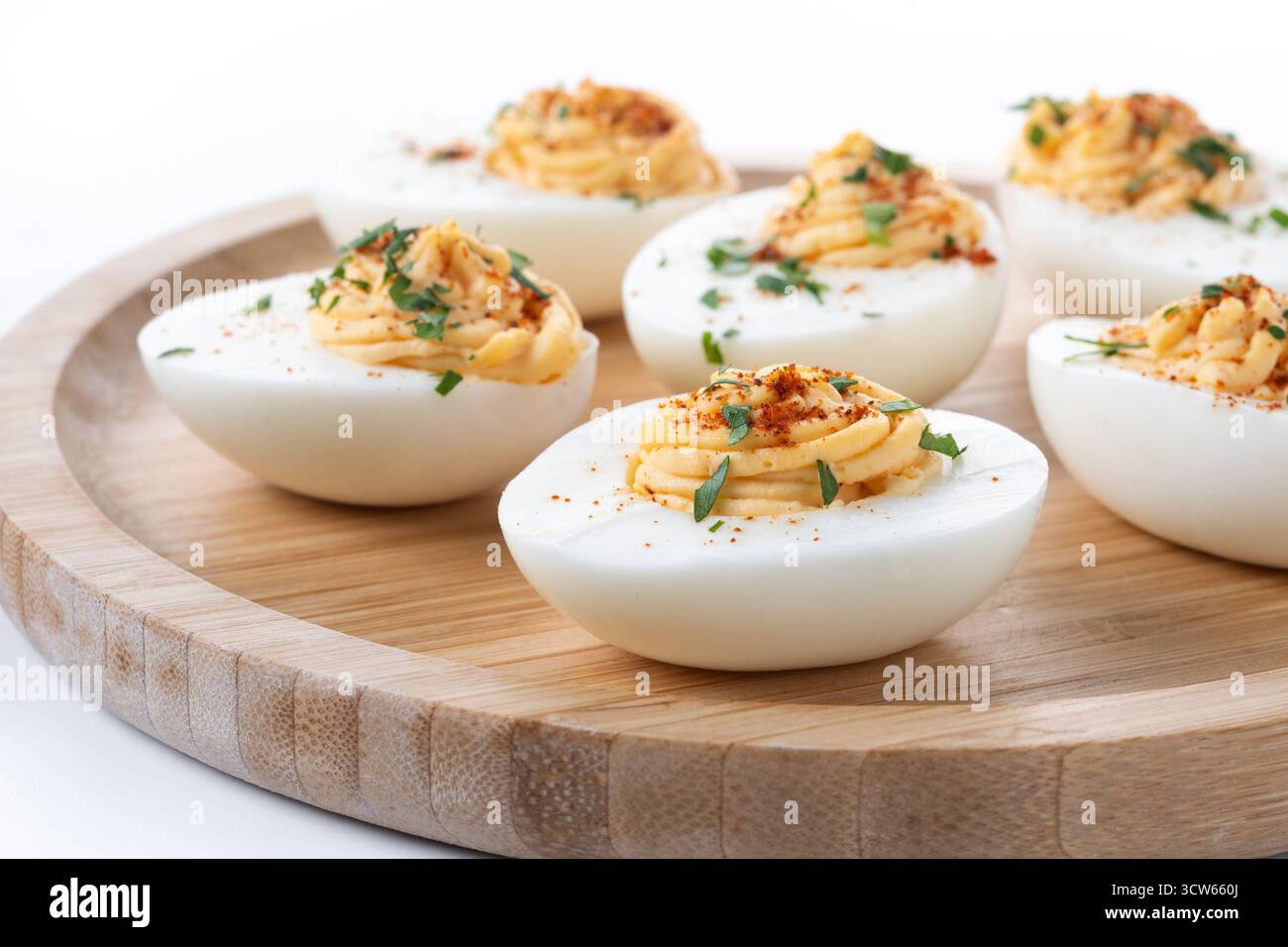 Homemade hard Boiled Deviled Eggs garnished with herbs isolated on white background. Stock Photo