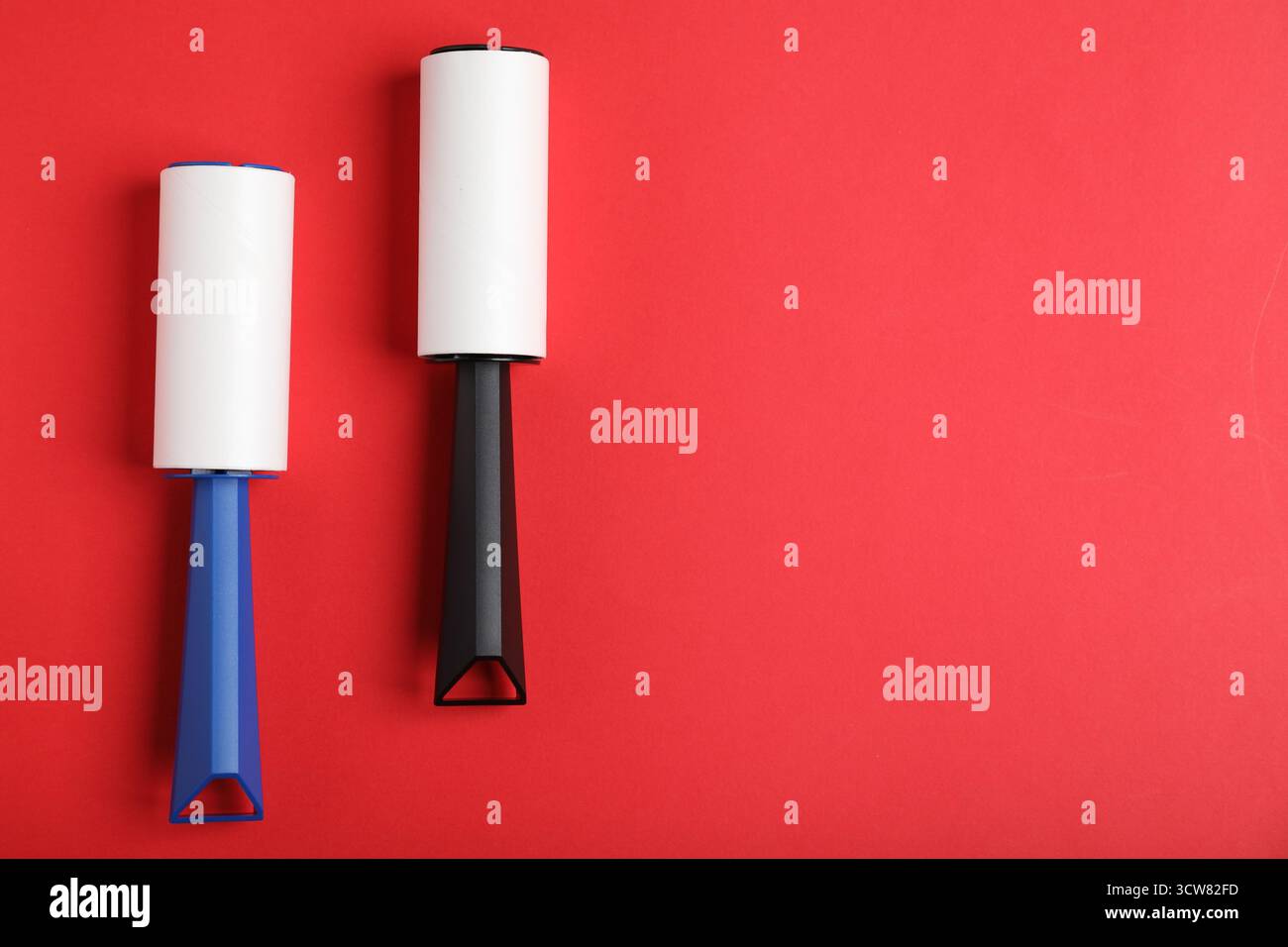 Two lint rollers on red background, flat lay. Space for text Stock Photo