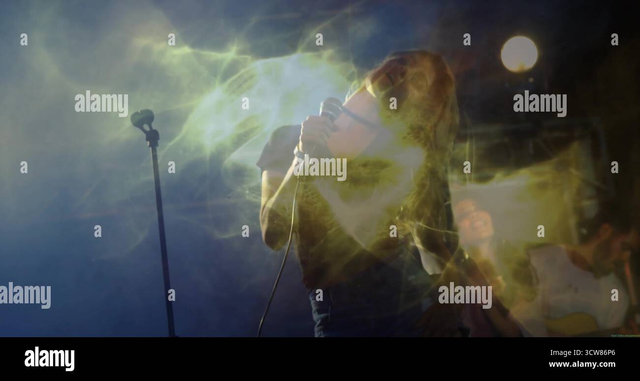Singing female performer in dark t-shirt and jeans on stage, with wired microphone and haze effects. Performance, concert, acoustic, entertainment, ni Stock Photo