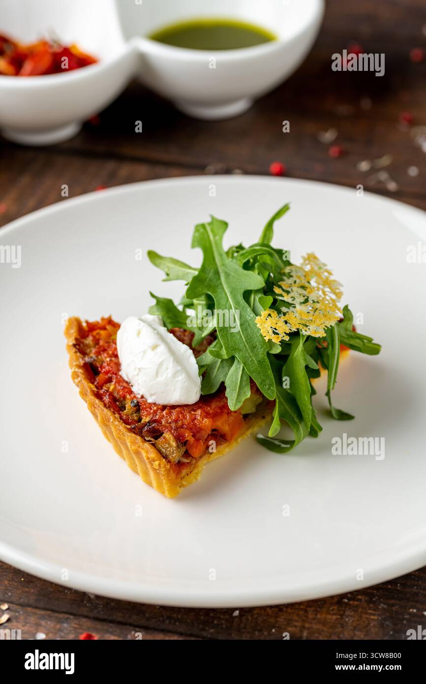 Mini tomato tart topped with burrata and peppery arugula garnish Stock Photo