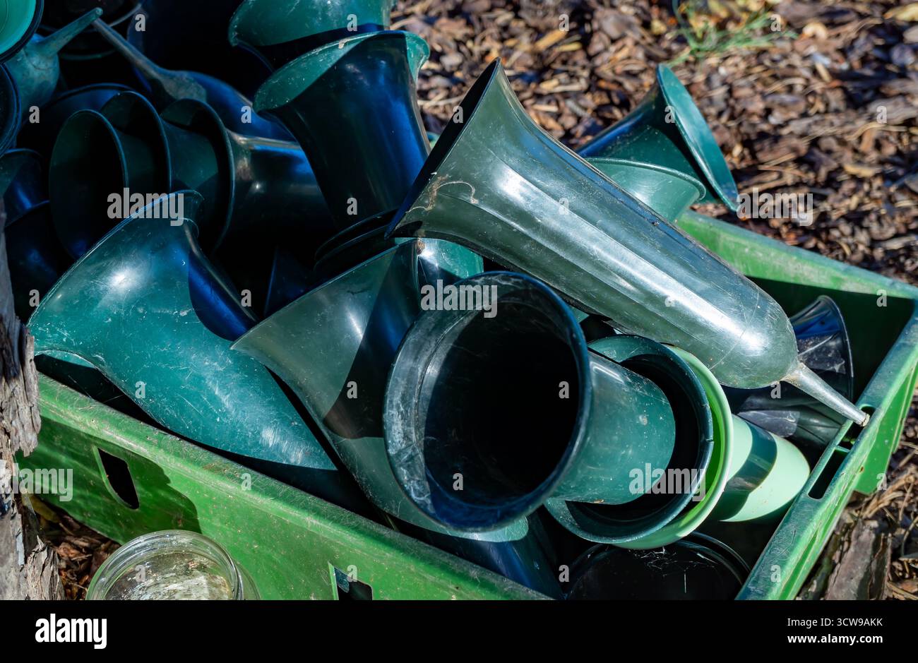 Close up of green plastic cemetery vases stacked in a box outdoors on a graveyard, used for flowers and memorial decoration. Stock Photo