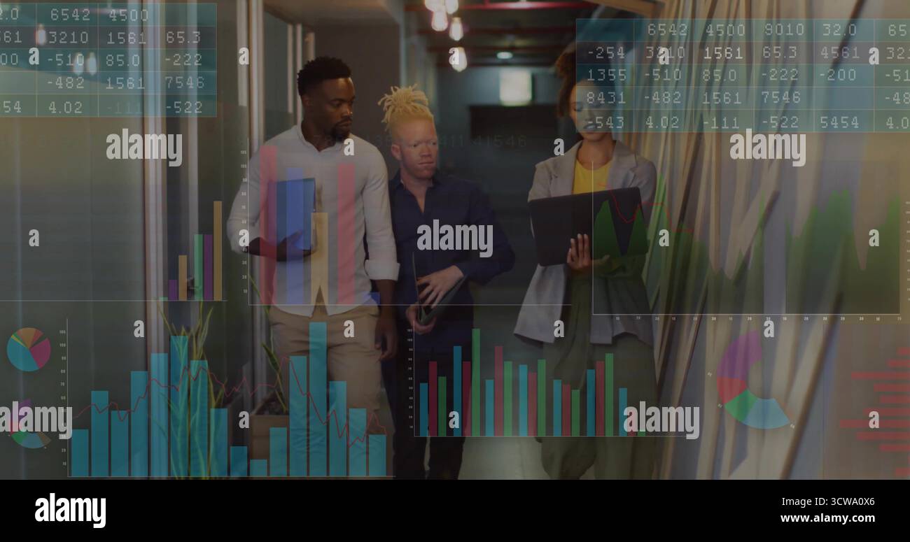 Walking team analyzing data in office corridor with blue folder, laptop, translucent charts, graphs Stock Photo