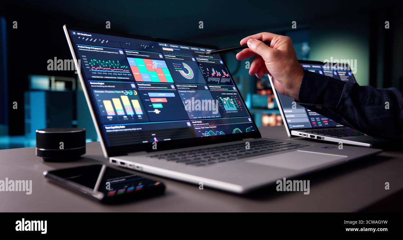 Senior Business Analyst Working Late On Predictive Data Management Dashboard Stock Photo