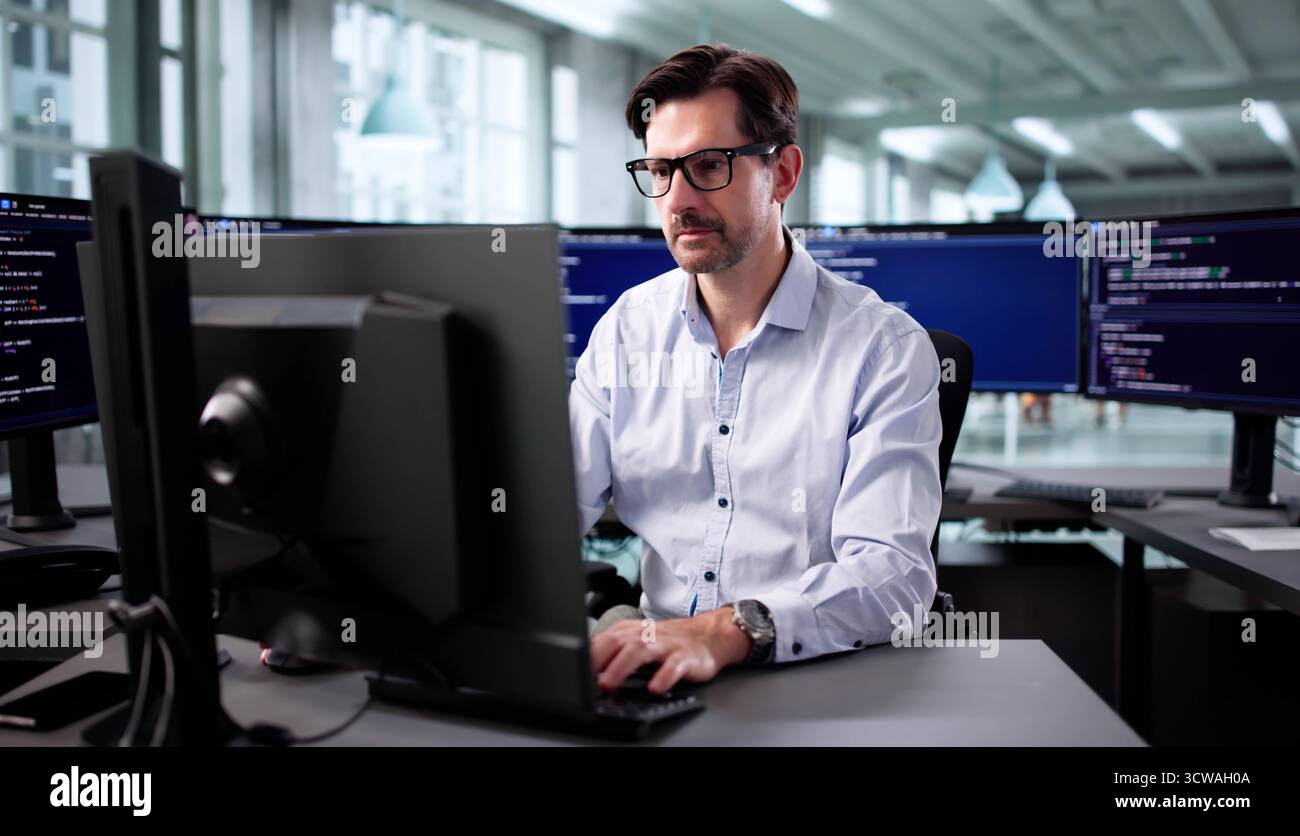 Senior Programmer Debugging Cyber Security Software At Desktop In Office Stock Photo