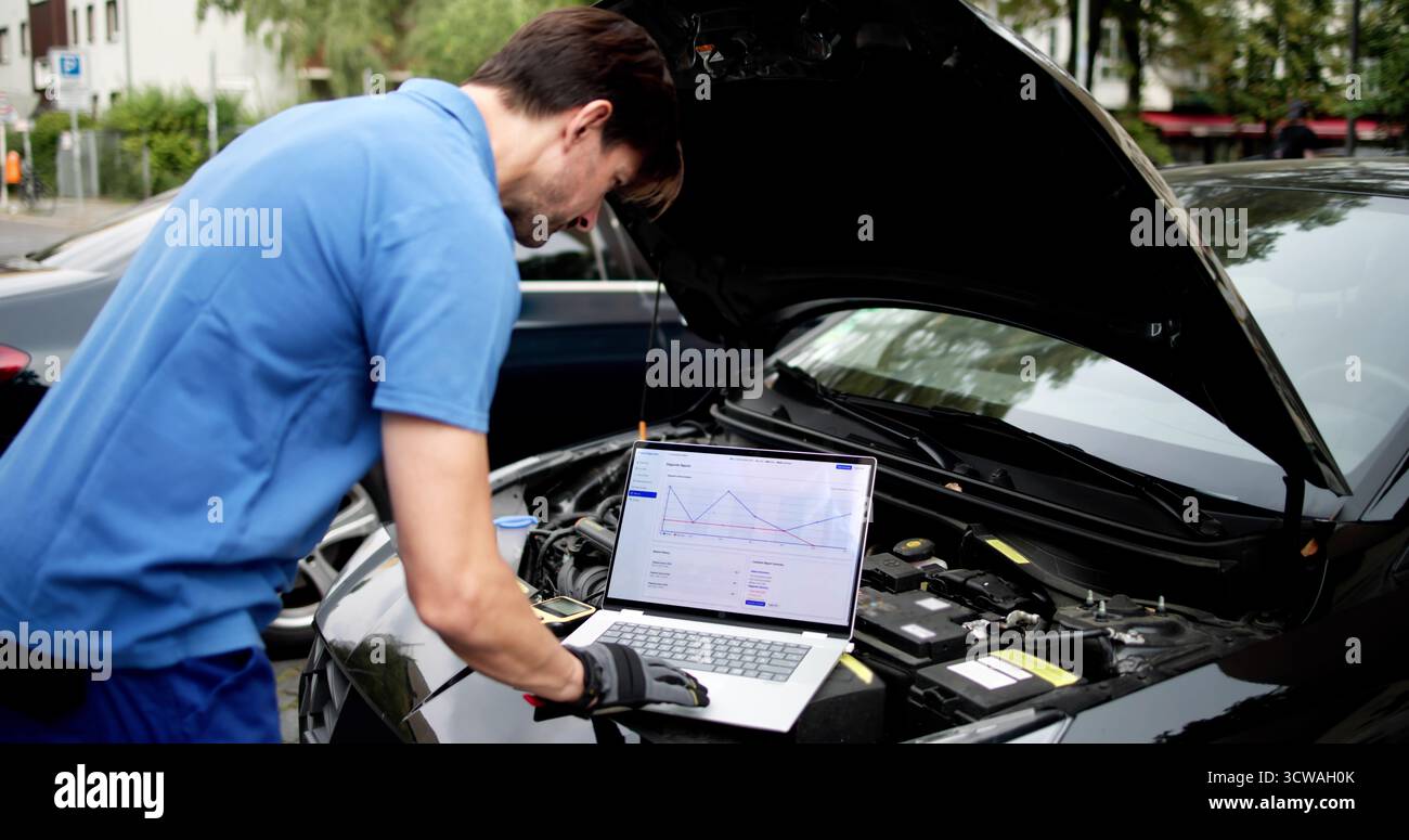 Skilled Senior Mechanic Using Laptop To Diagnose Car Engine Issues. Stock Photo