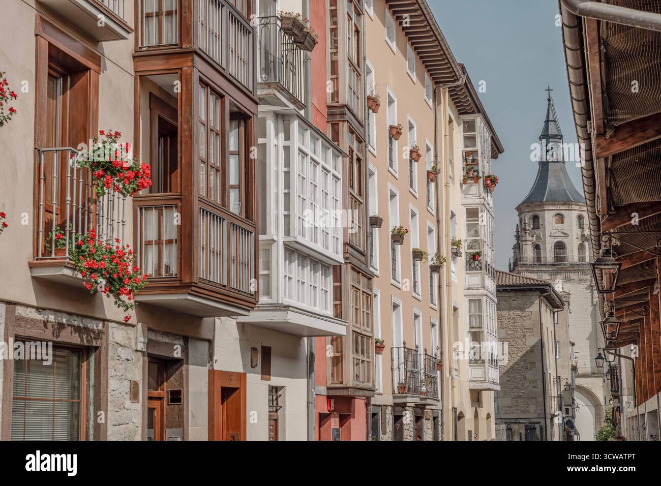 Charming narrow street in Vitoria-Gasteiz old town with colorful bay windows and flower balconies leading to cathedral. Historic Basque architecture f Stock Photo