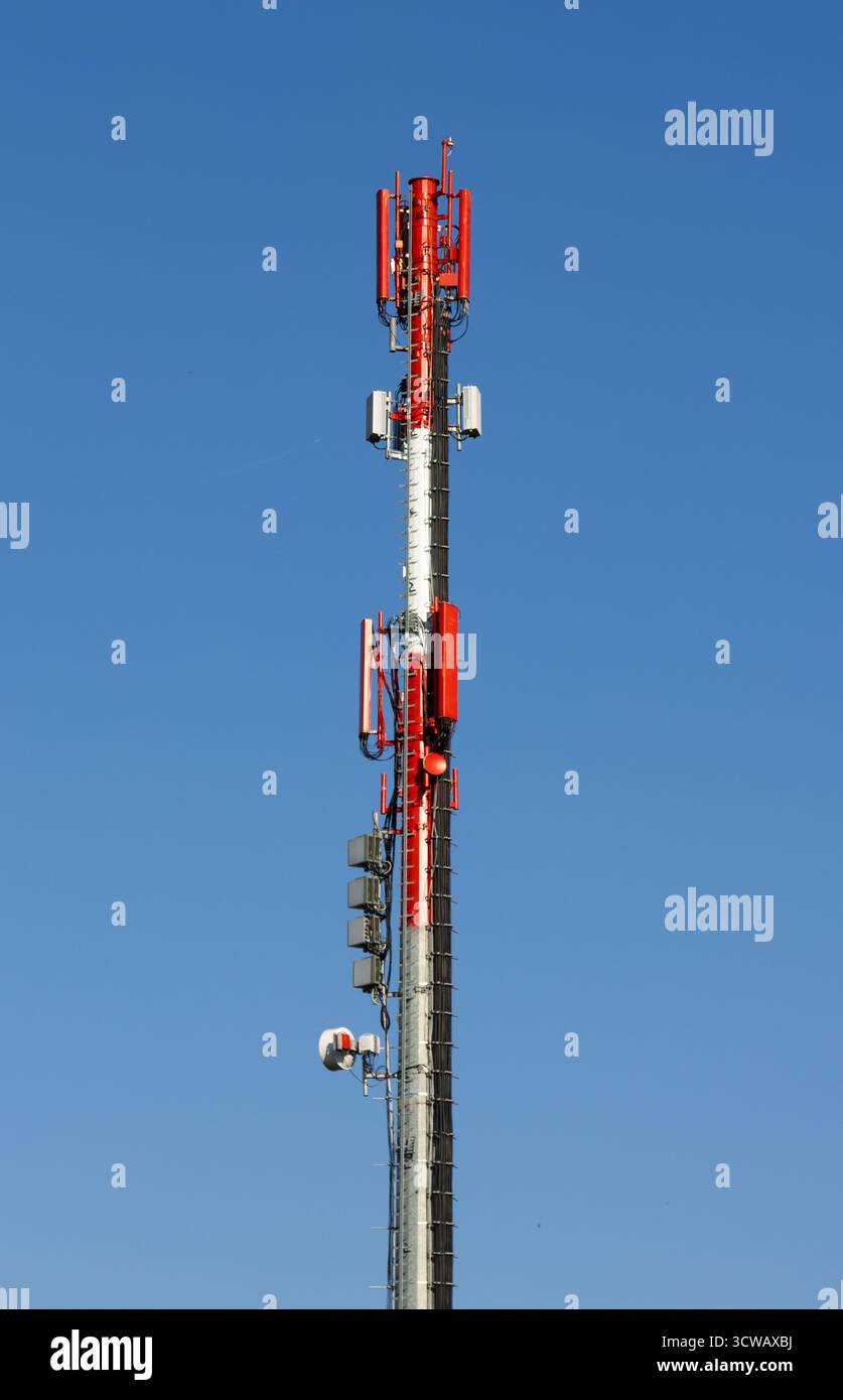 A tall telecommunication tower with red antennas stands against clear ...