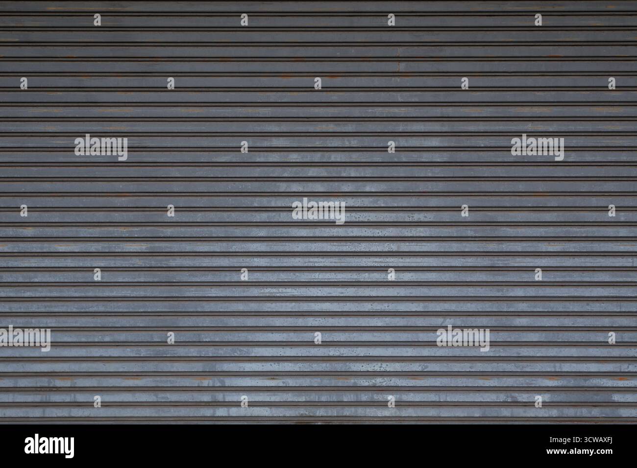 Front view of an old and weathered closed security roller door (or roller shutter, sectional overhead door, roll up or rolling garage door). Stock Photo