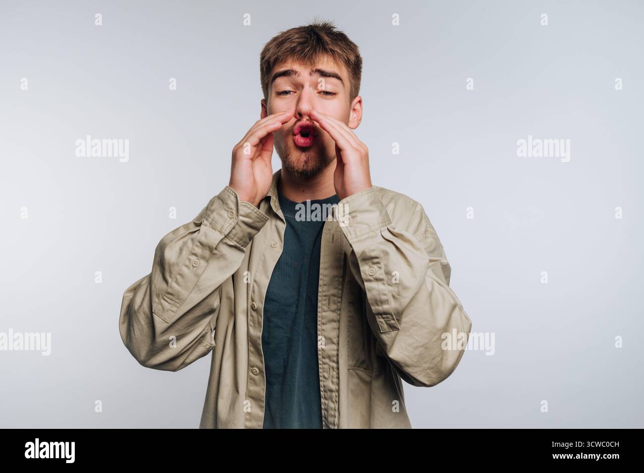 portrait of young man passionately shouts with expression, using his hands to convey strong emotions on white background Stock Photo