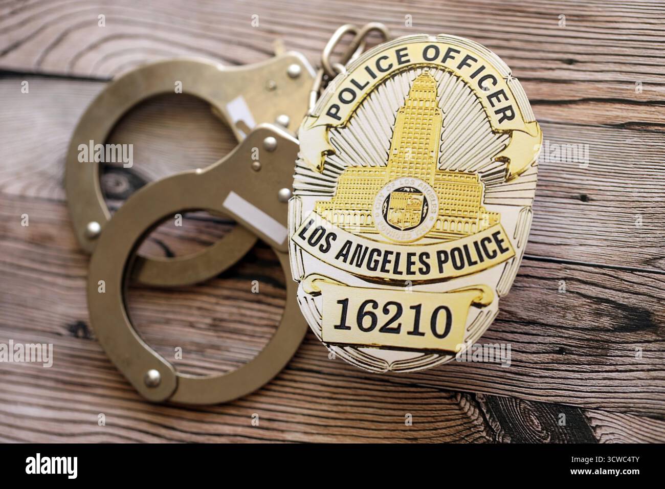 KYIV, UKRAINE - SEPTEMBER 17, 2025 US LAPD Police officer badge with handcuffs on wooden table close up Stock Photo