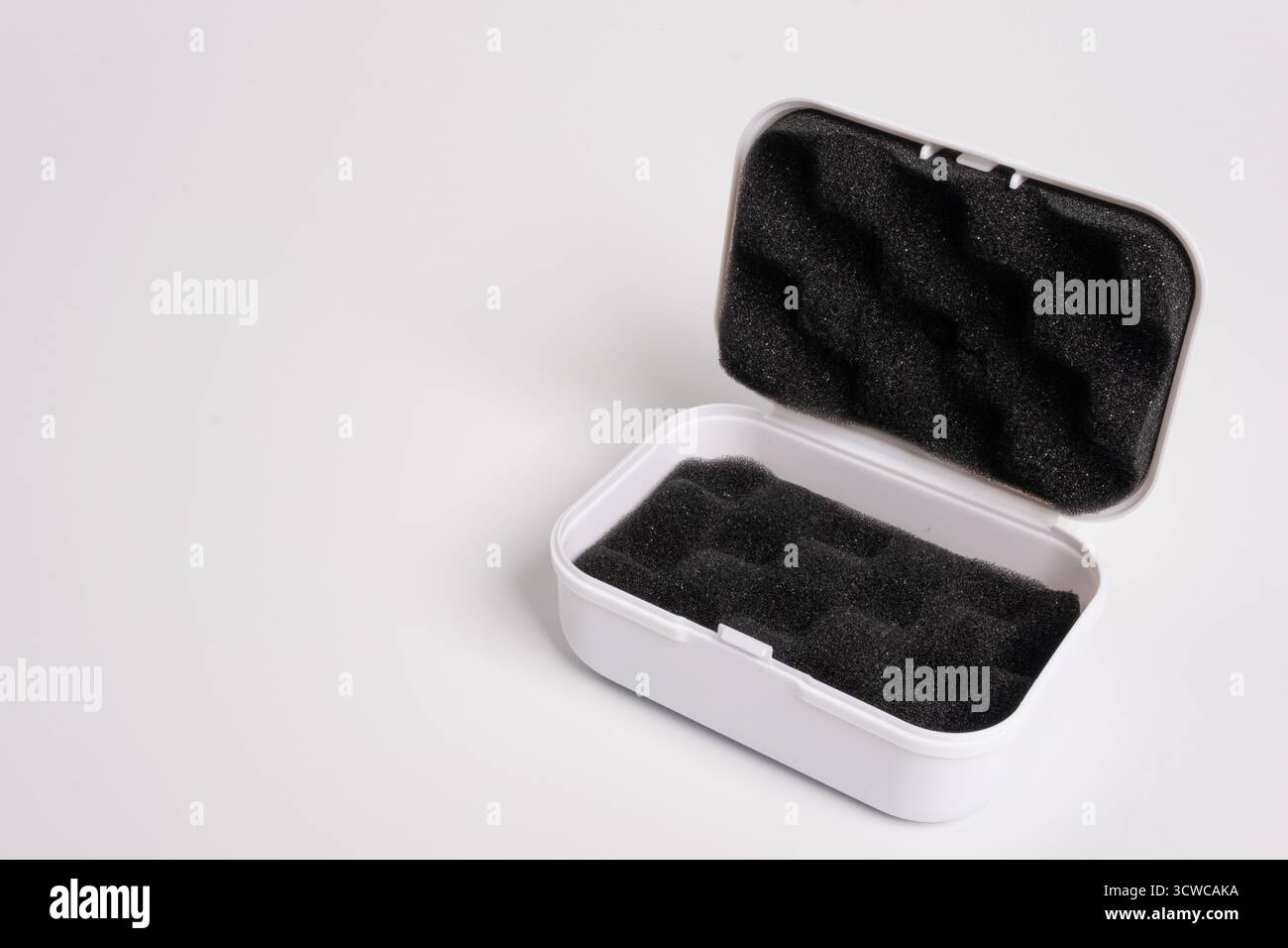 White open box lined with black sponge inside, isolated on a white background. Black mini pouch bag for storing small things. Inside of the protection Stock Photo
