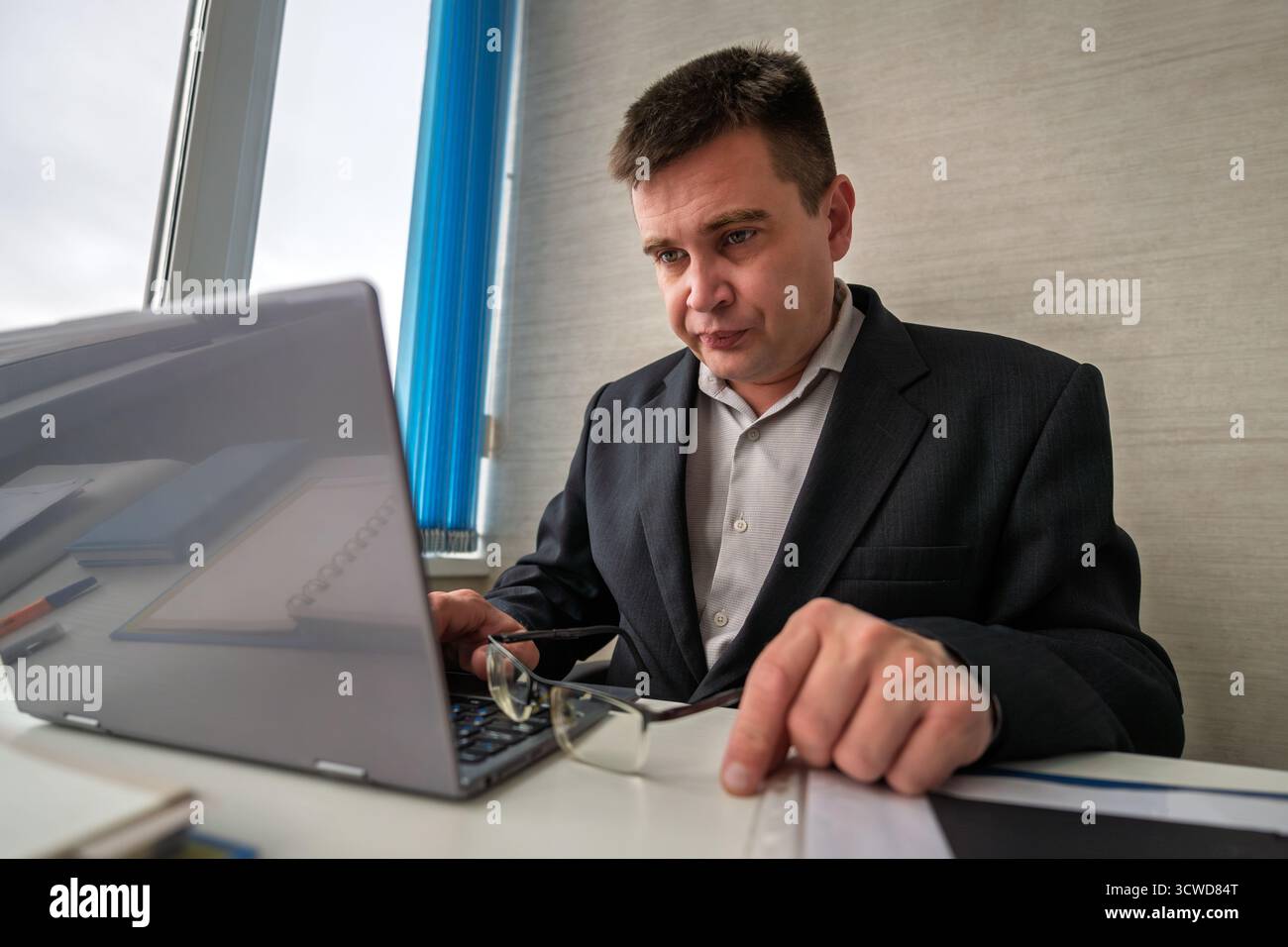 Thoughtful it developer thinking about fixing software bugs on netbook. contemplative male student watching tutorial on web site learning online via l Stock Photo