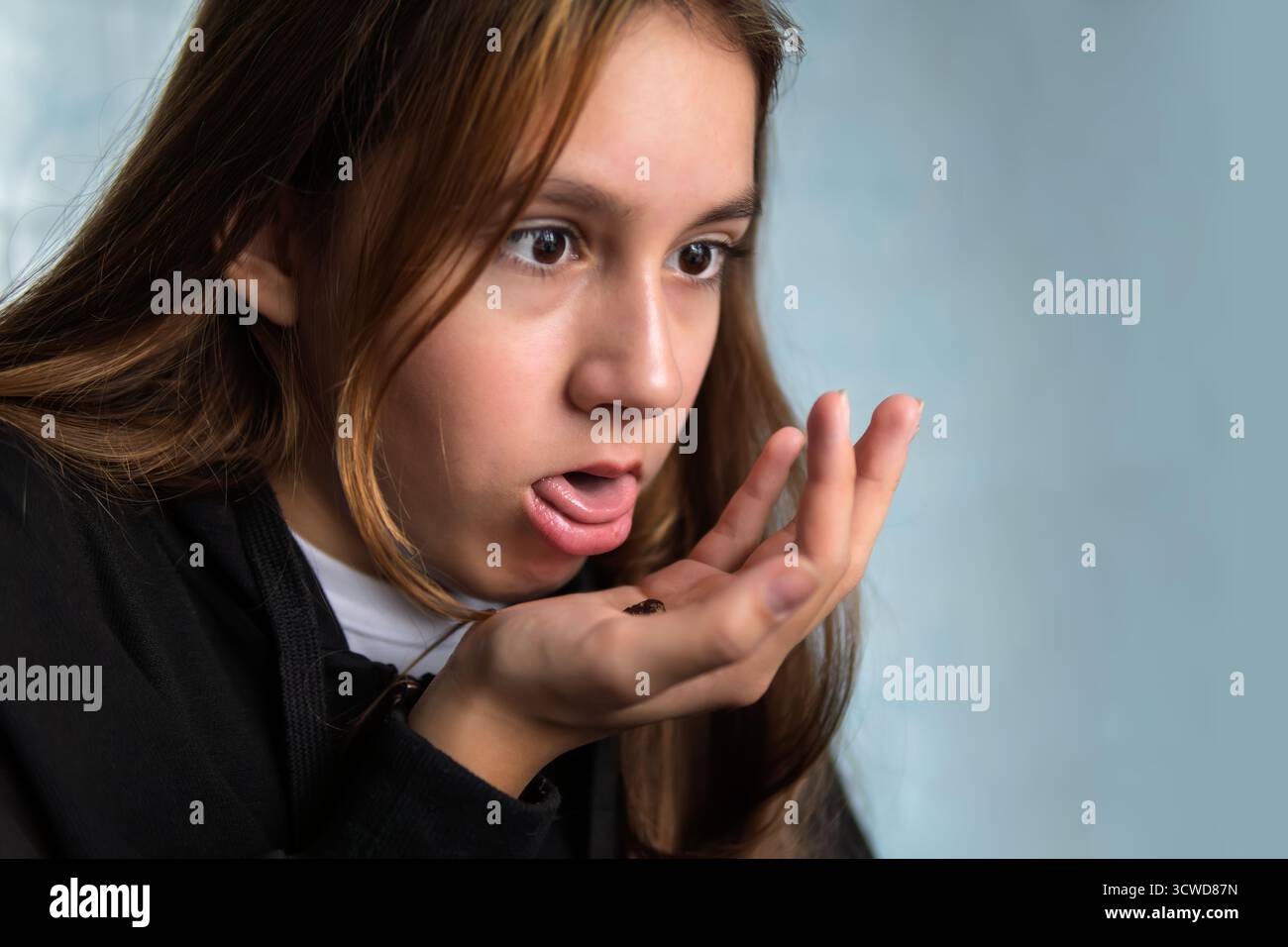 The girl spits out an unhealthy chocolate into her hand. Nasty, tasteless food. Harm and rejection of sweets concept Stock Photo