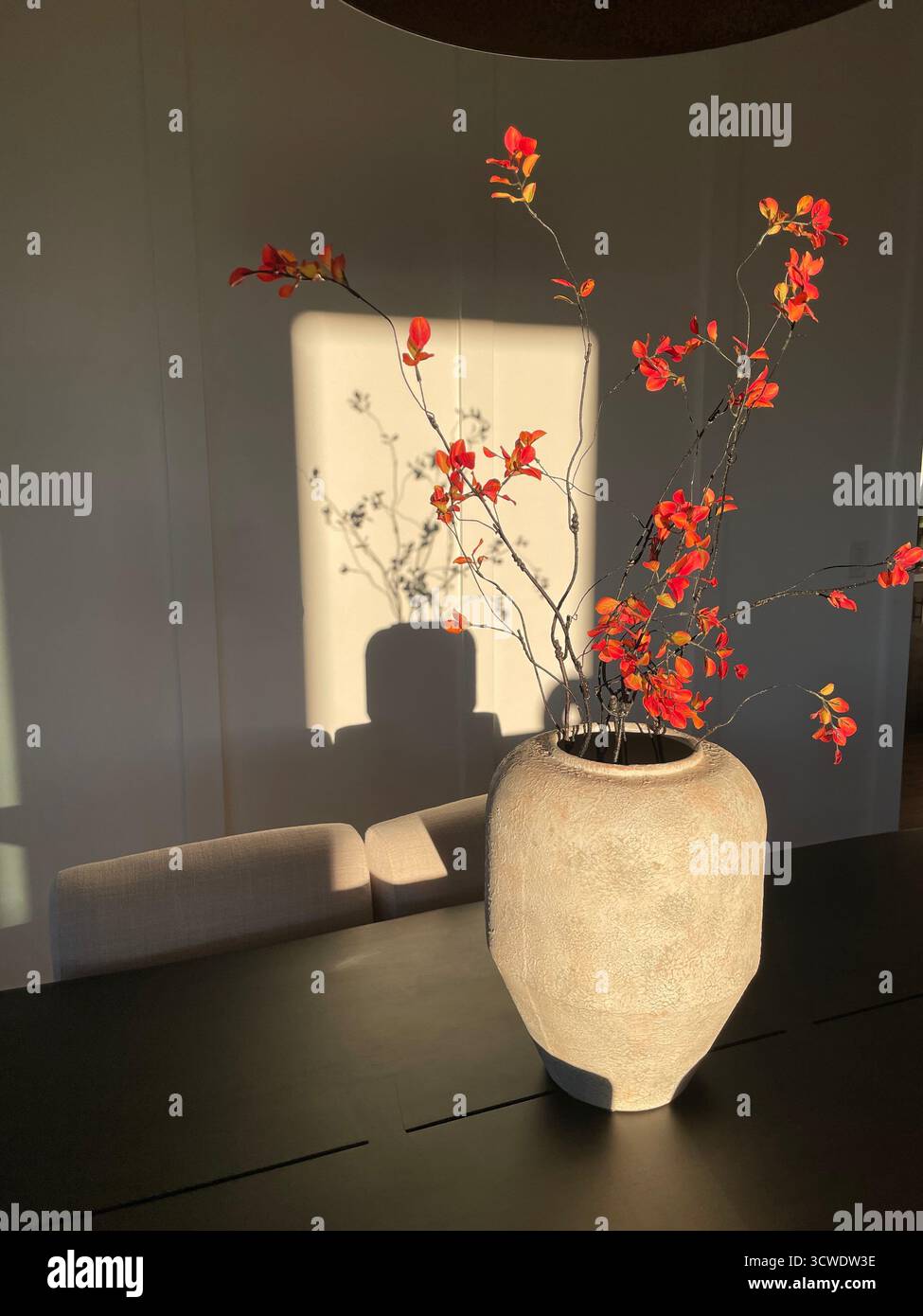 vase on table w/ branches, orange flowers - Smartphone Captured Stock Image