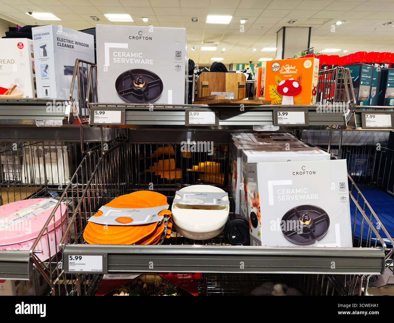 Manchester, UK - September 26, 2025: Display of ceramic serveware and orange silicone mats on metal shelves in a home goods store. Stock Photo