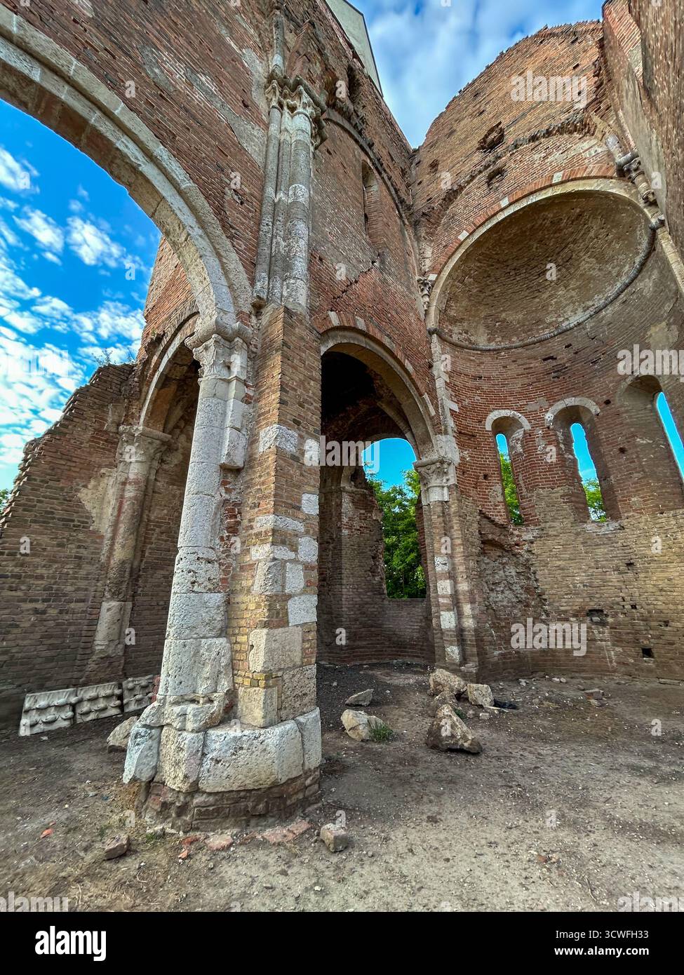 Stone pillars and arches of the Araca medieval Romanesque church near Novi Bečej, Serbia, showcasing centuries-old architecture against a bright blue - Smartphone Captured Stock Image