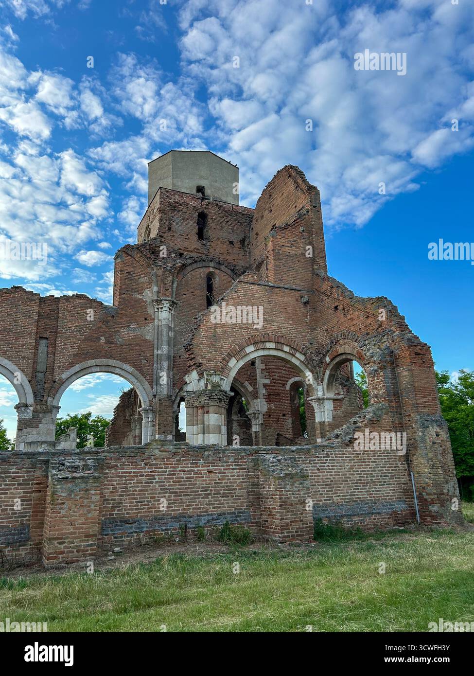 Old brick church ruins with arched windows and a tower under a vivid blue sky, showcasing medieval architecture and historic decay. - Smartphone Captured Stock Image